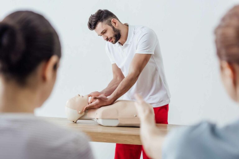 selective-focus-handsome-instructor-with-cpr-dummy-during-first-aid-training-class